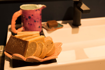 the washbasin ,soaps,candles and handmade ceramic bucket in the bath 