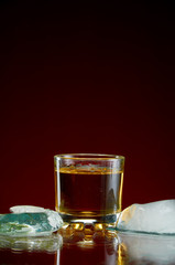 Glass with alcohol in a transparent glass with ice and mint on a red background