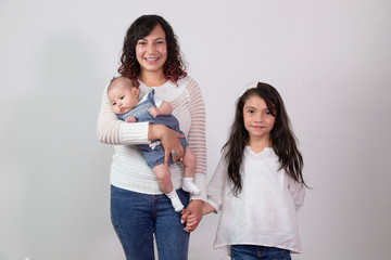 Mom with her cute baby in her arms while holding her eldest daughter by the hand while watching the...