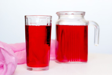 Fruit and berry red juice in glasses and jug on a white background. Fresh and cold summer drink.