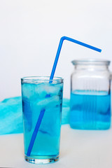Glass with a blue cocktail with ice on a white background. © Elena