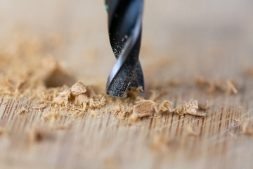 Close up of drill that pierces the wood. sawdust flies away