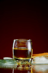 Strong alcoholic drink in a transparent glass with ice on a red background