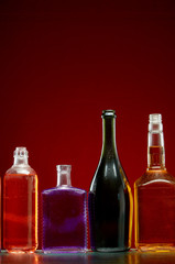 Different alcoholic drinks in transparent bottles on red background