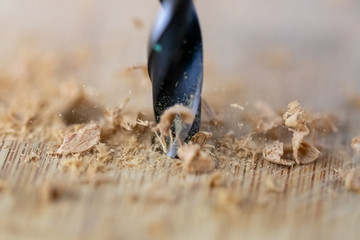Close up of drill that pierces the wood. sawdust flies away