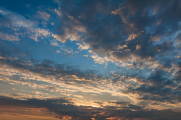 Naklejka na ściany i meble Dramatic evening sky with clouds painted by the setting sun