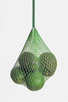 organic avocado in mesh bag on white background 
