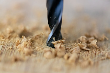 Close up of drill that pierces the wood. sawdust flies away