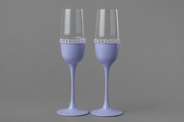 Two wedding wine glasses in lavender color on gray background.