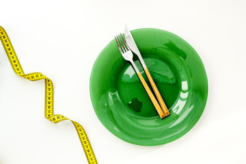Slim concept with plate, flatware and measuring tape on white background top view