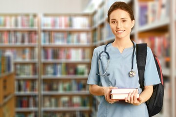 Nurse student with books and stethoscope in library