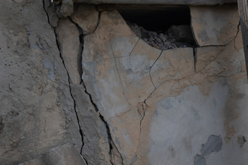 part of the old collapsing wall with cracks and loose plaster pieces close up