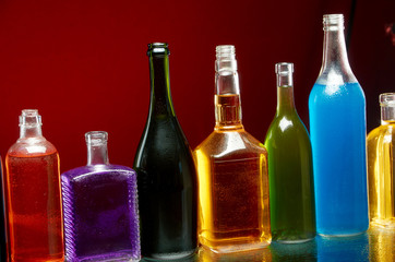 Different alcoholic drinks in transparent bottles on red background