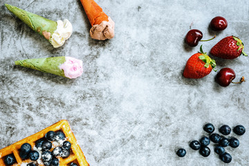 Background of tasty and sweet foods with red fruits and waffles, with negative space for summery design.