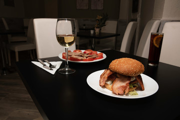 Delicious table set to eat, a delicious burger with a glass of wine and another dish more