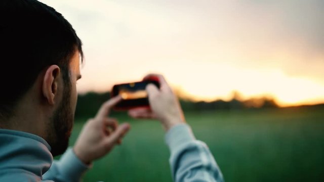 young man photographing the landscape on the camera of a smartphone
