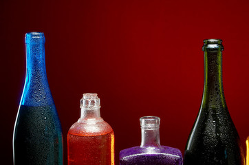 Different alcoholic drinks in transparent bottles on red background