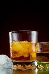 Strong alcohol in a transparent glass with ice on a red background