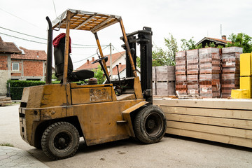 Fork lifter holding a stack of rough sawn timber pine lumber construction material at the building site