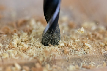 Close up of drill that pierces the wood. sawdust flies away