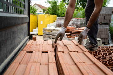 Construction worker loading material in the lorry truck at the warehouse for the building site clay brick blocks