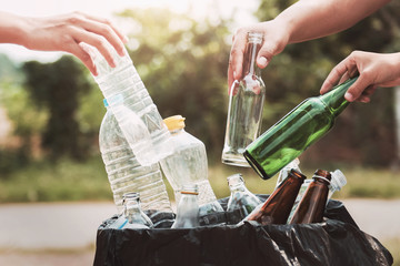 people hand holding garbage bottle plastic and glass putting into recycle bag for cleaning