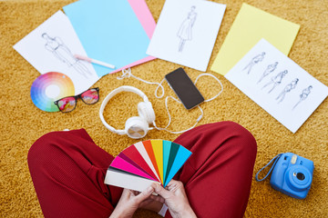Fototapeta premium View of female designer with color swatches sitting on the floor while working over new fashion collection at home