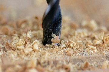 Close up of drill that pierces the wood. sawdust flies away