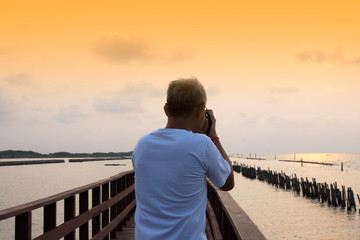 Old Man Holding Camera DSLR Take Photo on Bridge at Sea View on Morning