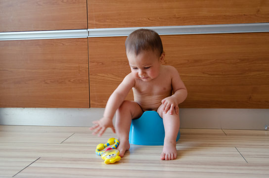 cute six months old baby boy siting on the blue potty