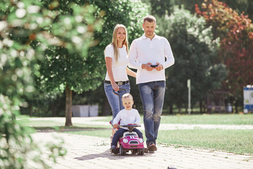 mom, dad, and son walking down a path in a city Park.