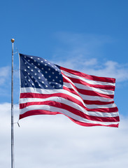 Vertical American Flag on Flag Pole with Blue Sky and Clouds