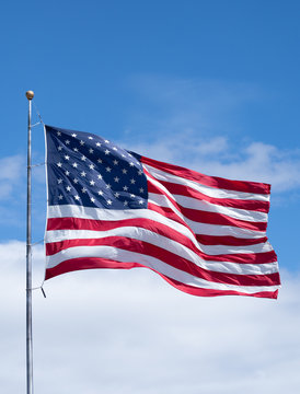 Vertical American Flag on Flag Pole with Blue Sky and Clouds
