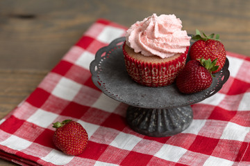 Homemade Strawberry Cupcake Isolated on Stand; Red Checked Napkin; Wooden Table; Fresh Strawberries