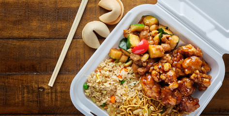 chinese take out with fried rice and general tsos chicken on table top panorama