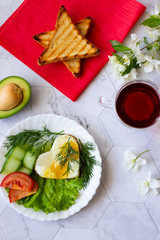 Fried eggs with lettuce, cucumber and tomato slices on a light background
