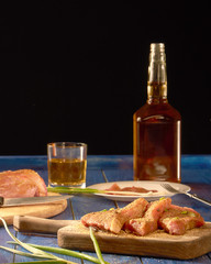 Fresh meat with spices on wooden Board and alcohol standing on blue table and black background
