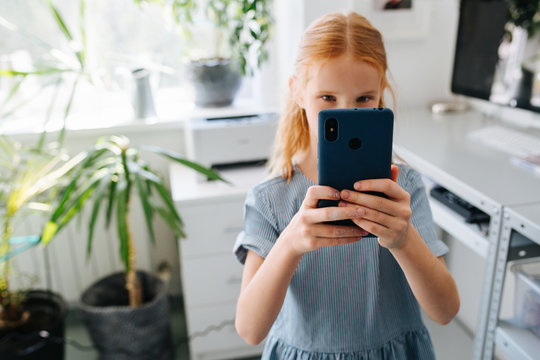 Teenage redhead girl is taking picture with her smartphone