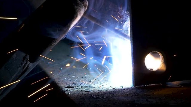 close up slow motion shot of arc welding at a fabrication shop in Hawaii, beautiful in and out of focus shots of smoke and blue arc fusing metal together