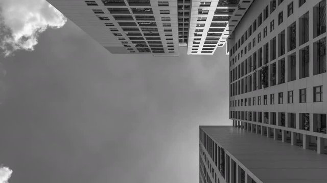 4k Black and White Time Lapse from low angle looking up to architecture and dramatic clouds moving left to right through the scene. Sun is flaring into the lens.