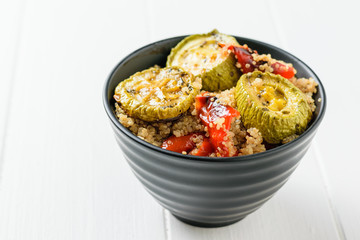 Baked bell peppers, zucchini and boiled quinoa on a white table. Vegetarian dish.