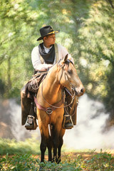 cowboy with his purebred horse standing in the forest