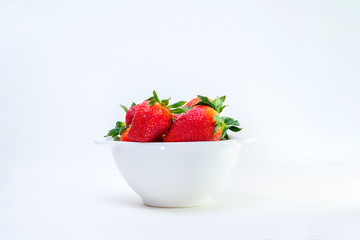 white bowl full of strawberries on white background in the center
