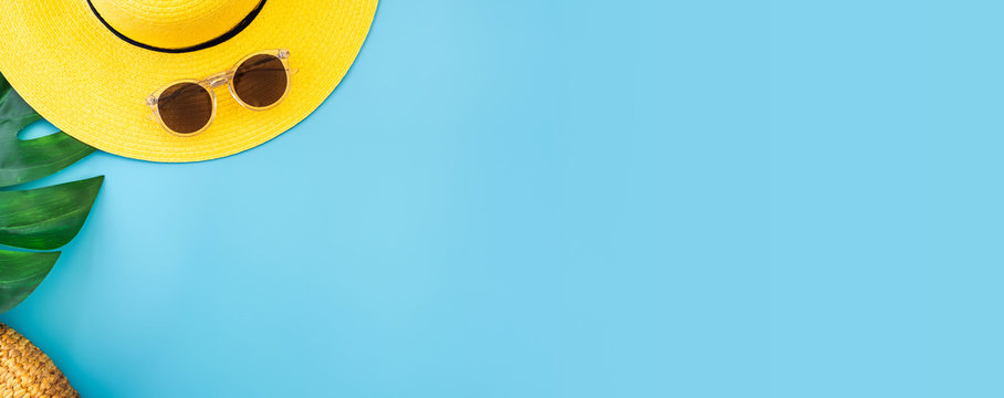 summer blue banner with yellow hat ,sunglasses and monstera leaf on blue background top view.