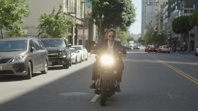 Businessman drives old school motorcycle on streets of downtown. Speed driving. Reaching a destination.