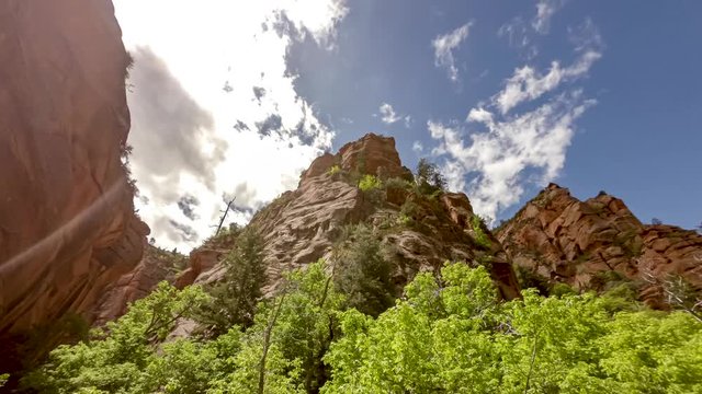 Looking up from a slot canyon to view red cliffs and a dramatic cloudscape - time lapse