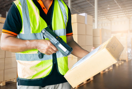 warehouse inventory management. distribution warehouse and logistics. warehouse worker in uniform is scanning bar code scanner with parcel box. 