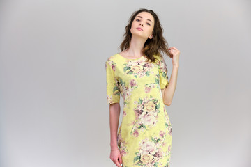 Obraz premium Life is a success. I am pleased with myself. Concept photo of a happy smiling woman satisfied life contented brunette girl in a yellow dress on a gray background with flowing hair.