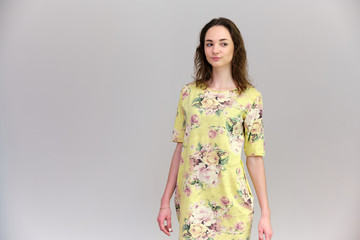 Obraz premium Life is a success. I am pleased with myself. Concept photo of a happy smiling woman satisfied life contented brunette girl in a yellow dress on a gray background with flowing hair.