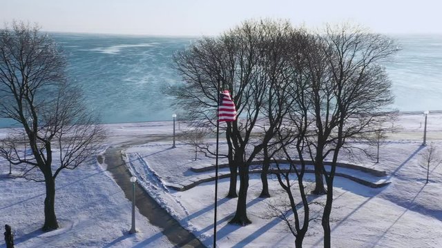American Flag Snow & Ice on Michigan Lake in Chicago Drone Shot City Flag Pole